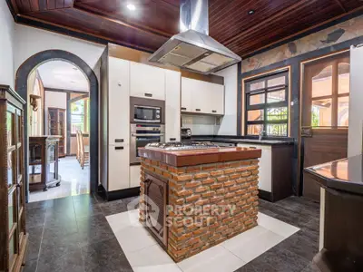 Charming rustic kitchen with brick island and modern appliances, featuring a cozy open layout and wooden ceiling.