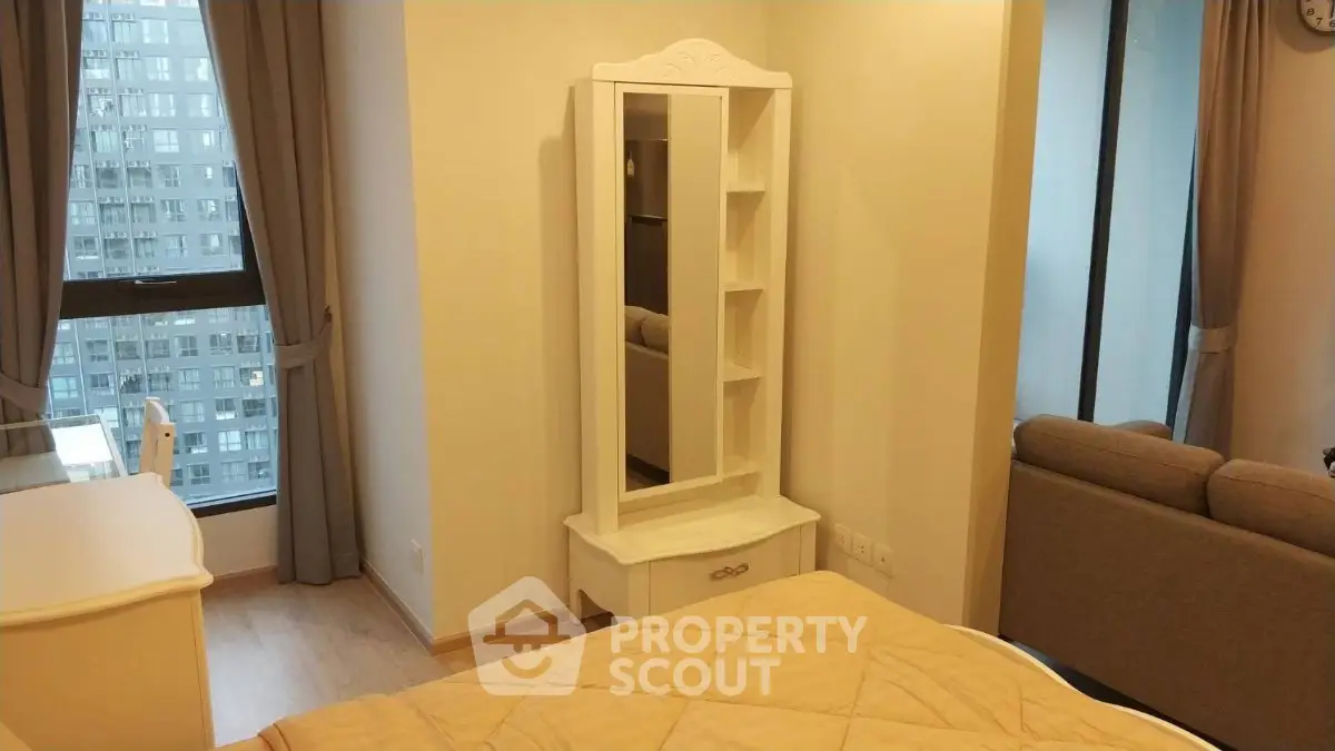 Cozy bedroom with elegant decor and city view, featuring a stylish mirror and comfortable seating area.