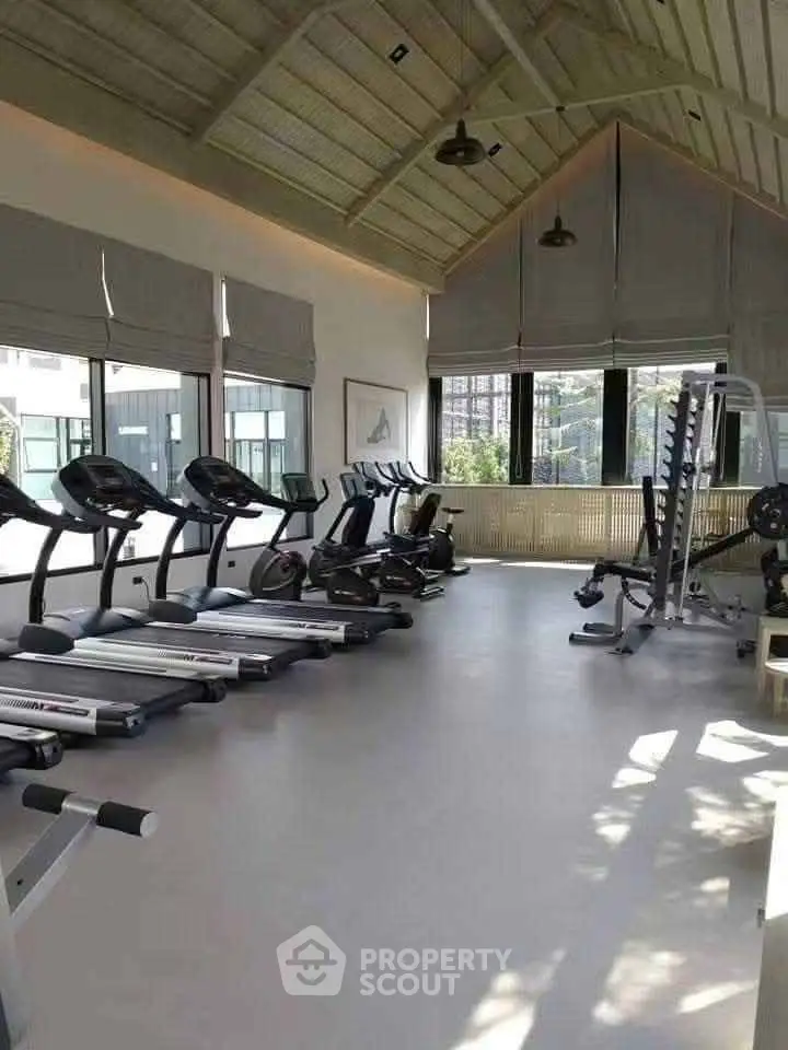 Spacious modern gym with state-of-the-art equipment and large windows for natural light.