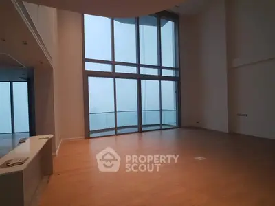 Spacious modern living room with floor-to-ceiling windows and balcony access.