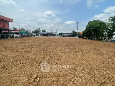 Spacious vacant land plot with potential for development under a clear blue sky.