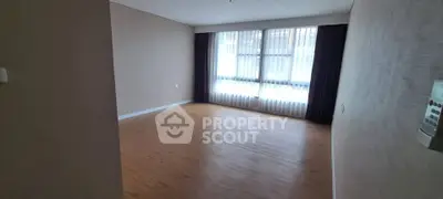 Spacious empty room with large window and wooden flooring, perfect for customization.