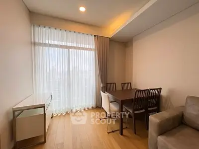 Modern living room with wooden flooring, dining table, and large window with sheer curtains.