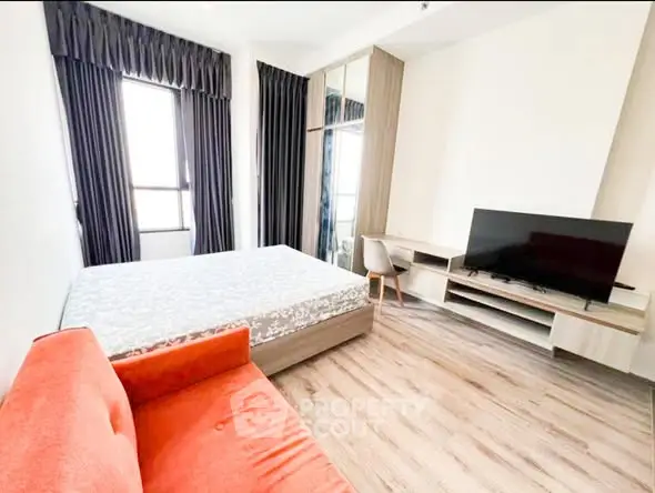 Modern bedroom with large bed, TV, and stylish orange sofa.