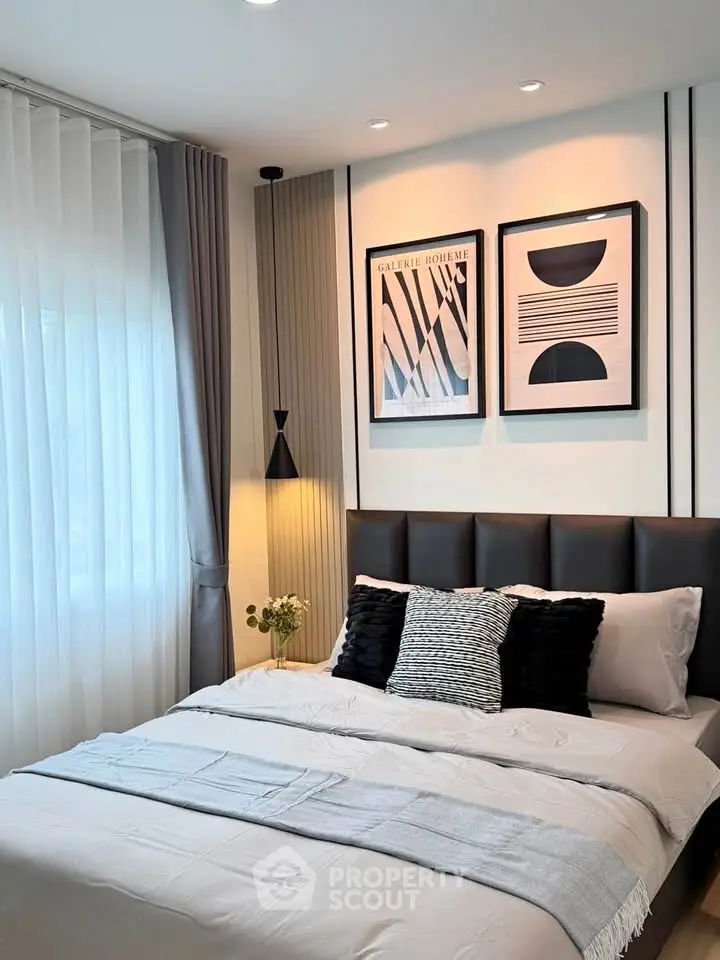 Modern bedroom with stylish decor and natural light, featuring elegant wall art and cozy bedding.