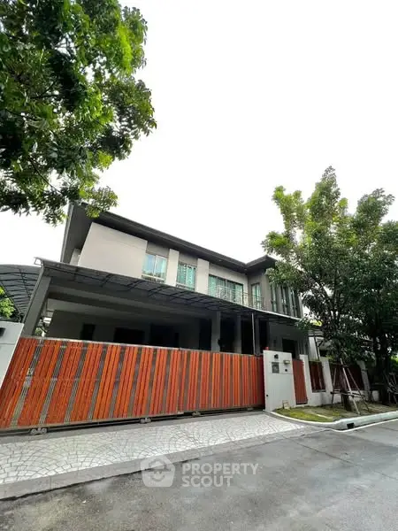 Modern two-story house with sleek design and wooden fence in a serene neighborhood.