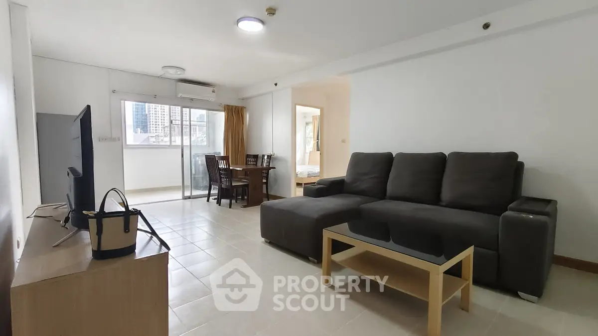 Spacious living room with modern furniture and city view balcony in urban apartment.