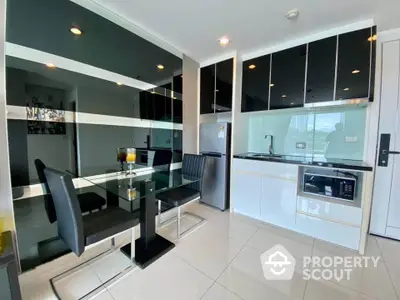 Modern kitchen with sleek black and white design, glass dining table, and built-in appliances