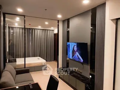 Modern living room with sleek design and integrated bedroom view, featuring stylish furniture and ambient lighting.