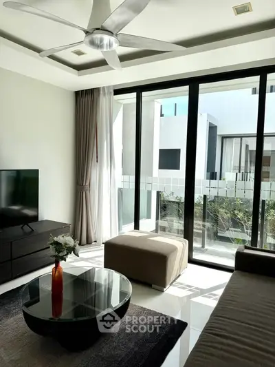 Modern living room with large windows and stylish decor, offering a bright and inviting atmosphere.