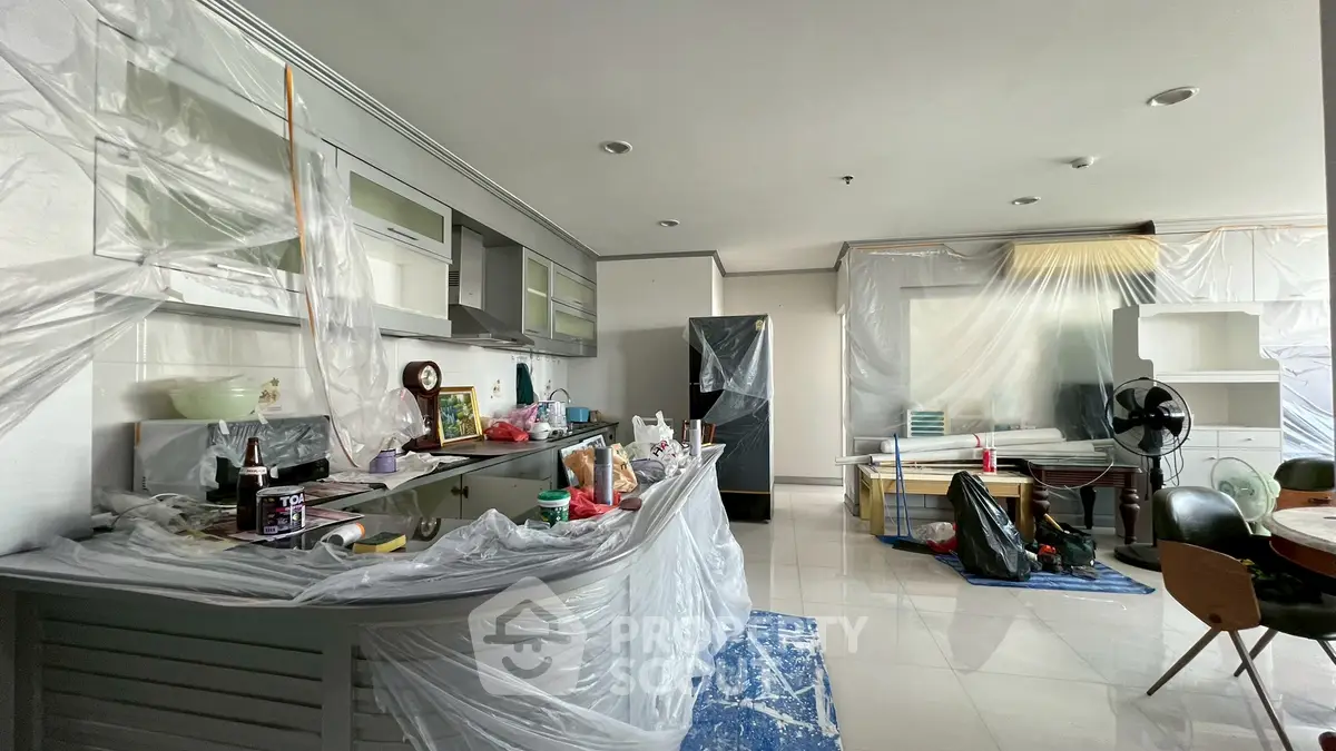 Spacious kitchen and living area under renovation with modern cabinets and appliances.