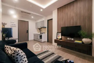 Modern living room with stylish decor and open kitchen layout, featuring a cozy sofa and wall-mounted TV.