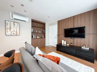 Modern living room with stylish decor, wall-mounted TV, and cozy seating area.