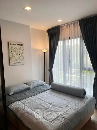 Cozy bedroom with large window and elegant curtains, perfect for relaxation.