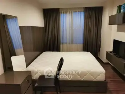 Modern bedroom with sleek furniture and large window, perfect for urban living.