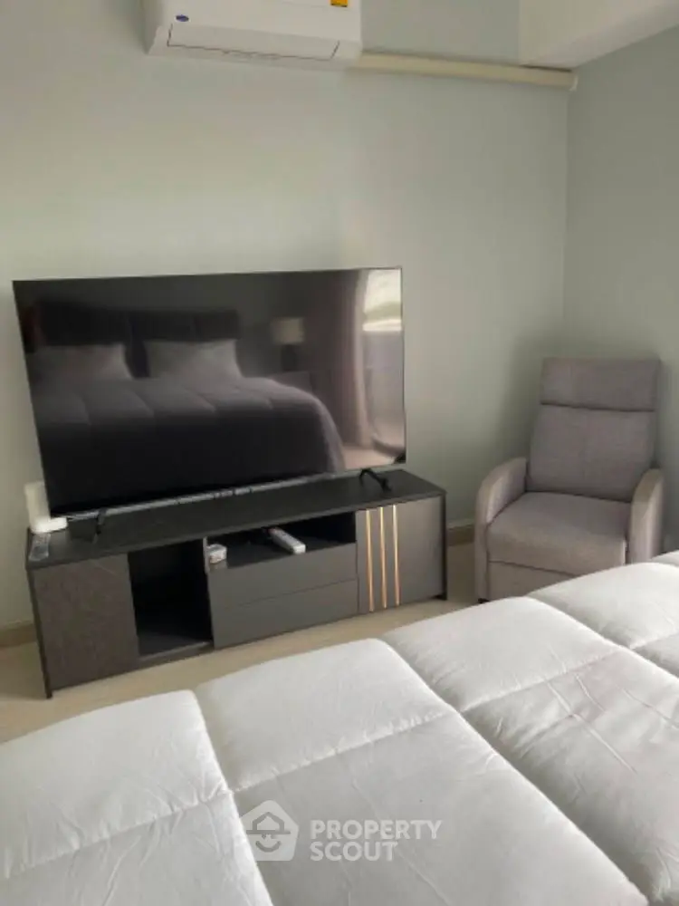 Modern bedroom with sleek TV setup and comfortable armchair