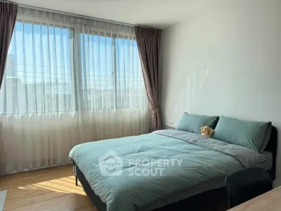 Bright and cozy bedroom with large windows and modern decor, perfect for relaxation.