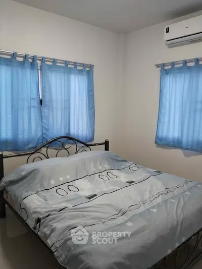 Cozy bedroom with blue curtains and air conditioning, perfect for relaxation.