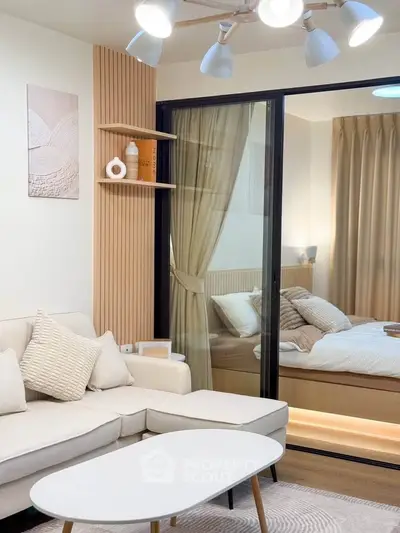 Modern living room with cozy sofa and view into elegant bedroom