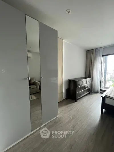 Spacious bedroom with modern wardrobe and balcony access in a stylish apartment.
