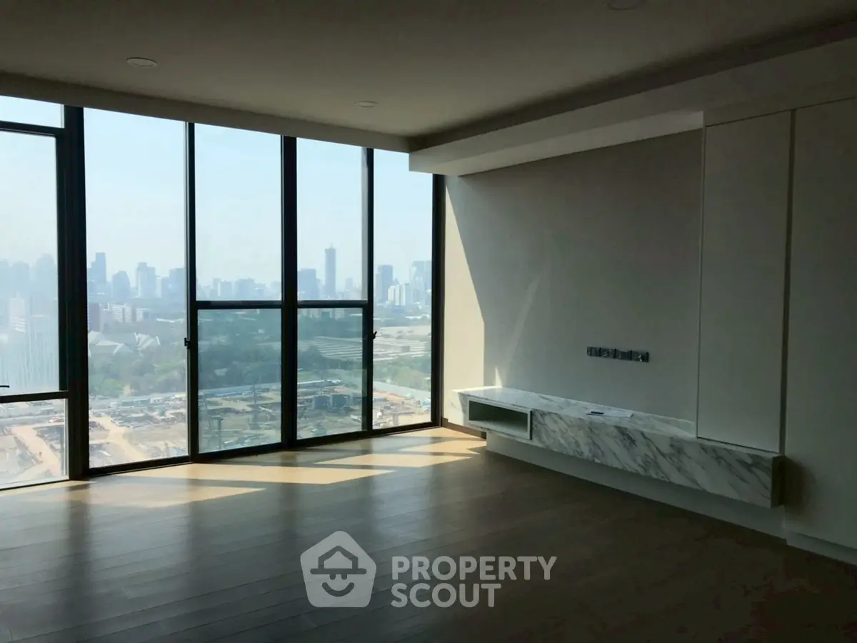 Spacious modern living room with floor-to-ceiling windows offering stunning city views.