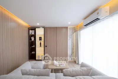 Modern living room with stylish decor and natural light, featuring a cozy sectional sofa and elegant shelving.