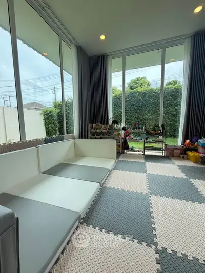 Spacious living room with large windows and garden view, perfect for family gatherings.