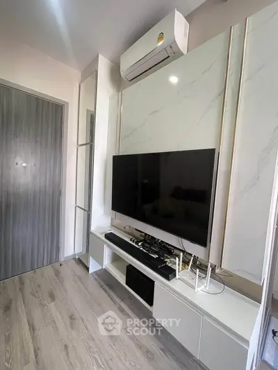 Modern living room with sleek TV setup and air conditioning in a stylish apartment.