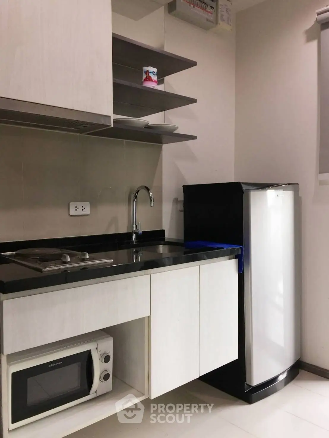 Modern compact kitchen with sleek white cabinets and appliances, perfect for urban living.
