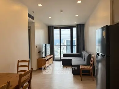Modern living room with large window and city view, featuring cozy furniture and sleek design.