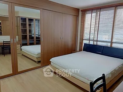 Spacious bedroom with mirrored wardrobe and large windows for natural light.