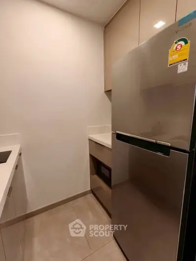 Modern kitchen with sleek fridge and built-in microwave in compact layout.