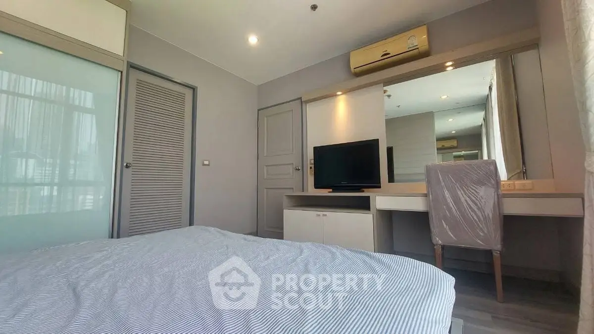 Modern bedroom with stylish decor and large mirror, featuring a cozy bed and sleek furniture.