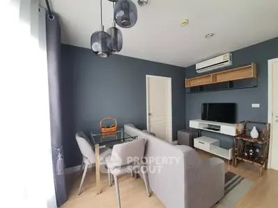 Modern living room with stylish decor, featuring a cozy sofa, glass dining table, and wall-mounted TV.