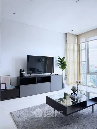 Modern living room with sleek furniture and large TV, offering a panoramic city view.