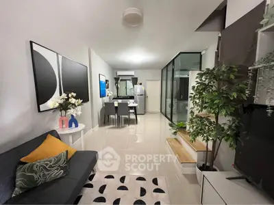 Modern living room with open layout, stylish decor, and sleek kitchen area.