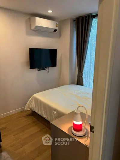 Cozy bedroom with modern decor, featuring a wall-mounted TV and air conditioning.