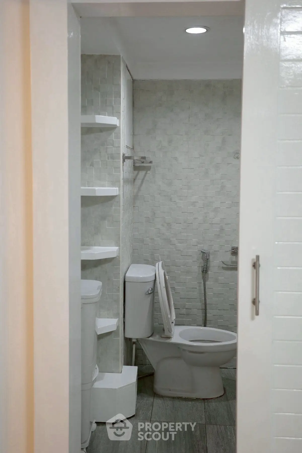 Modern bathroom with sleek design and efficient use of space, featuring a toilet and built-in shelves.