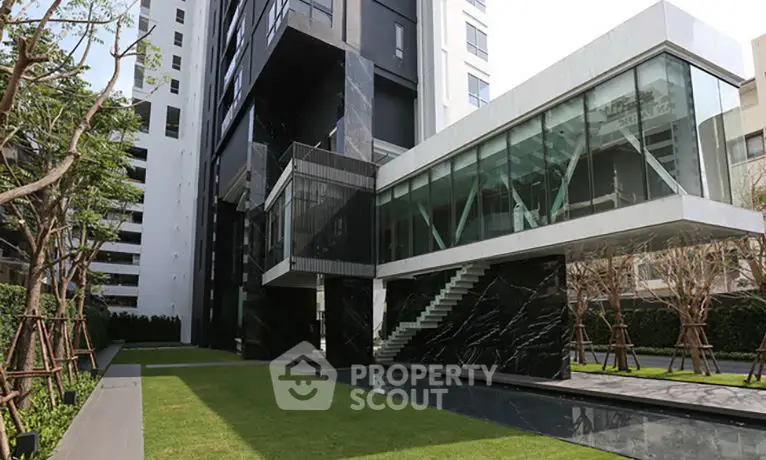 Modern luxury apartment building with sleek architecture and lush green garden.