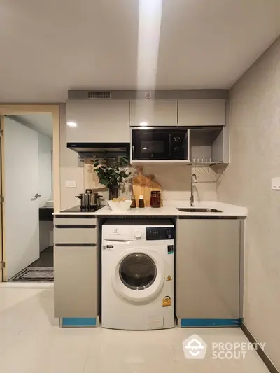 Modern compact kitchen with integrated washing machine and sleek cabinetry