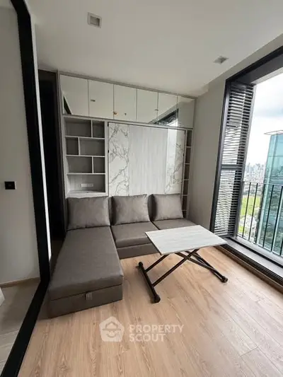 Modern living room with stylish sofa and balcony view in a high-rise apartment.