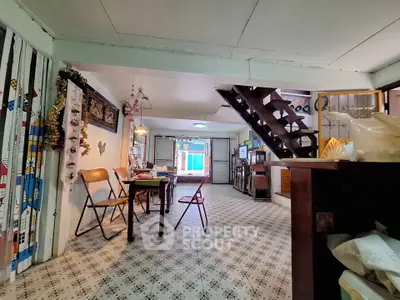 Charming vintage living room with patterned tile flooring and cozy dining area under a wooden staircase.