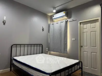 Modern bedroom with minimalist design featuring a metal bed frame and air conditioning unit.