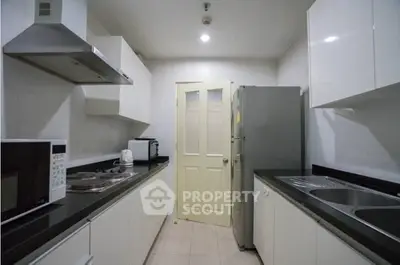 Modern kitchen with sleek white cabinets and stainless steel appliances in a compact layout.