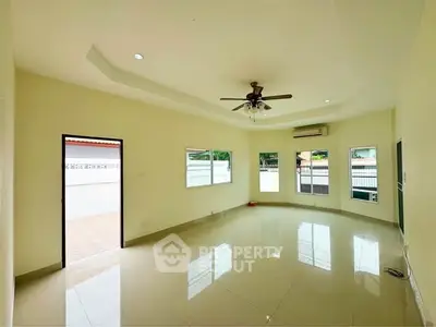 Spacious living room with ceiling fan and large windows offering natural light.