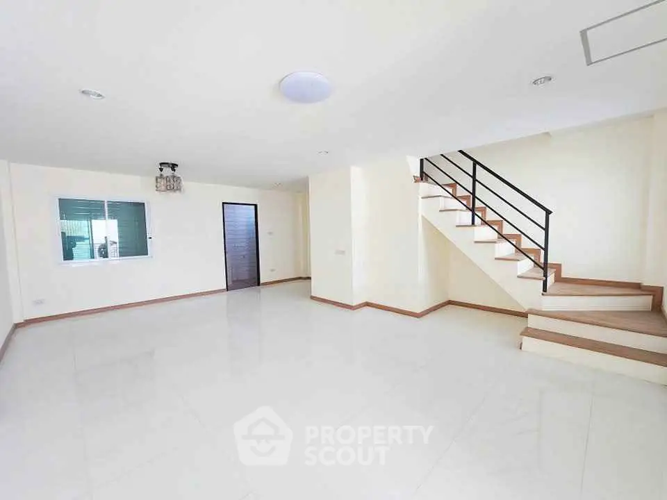 Spacious modern living room with sleek staircase and bright natural lighting.