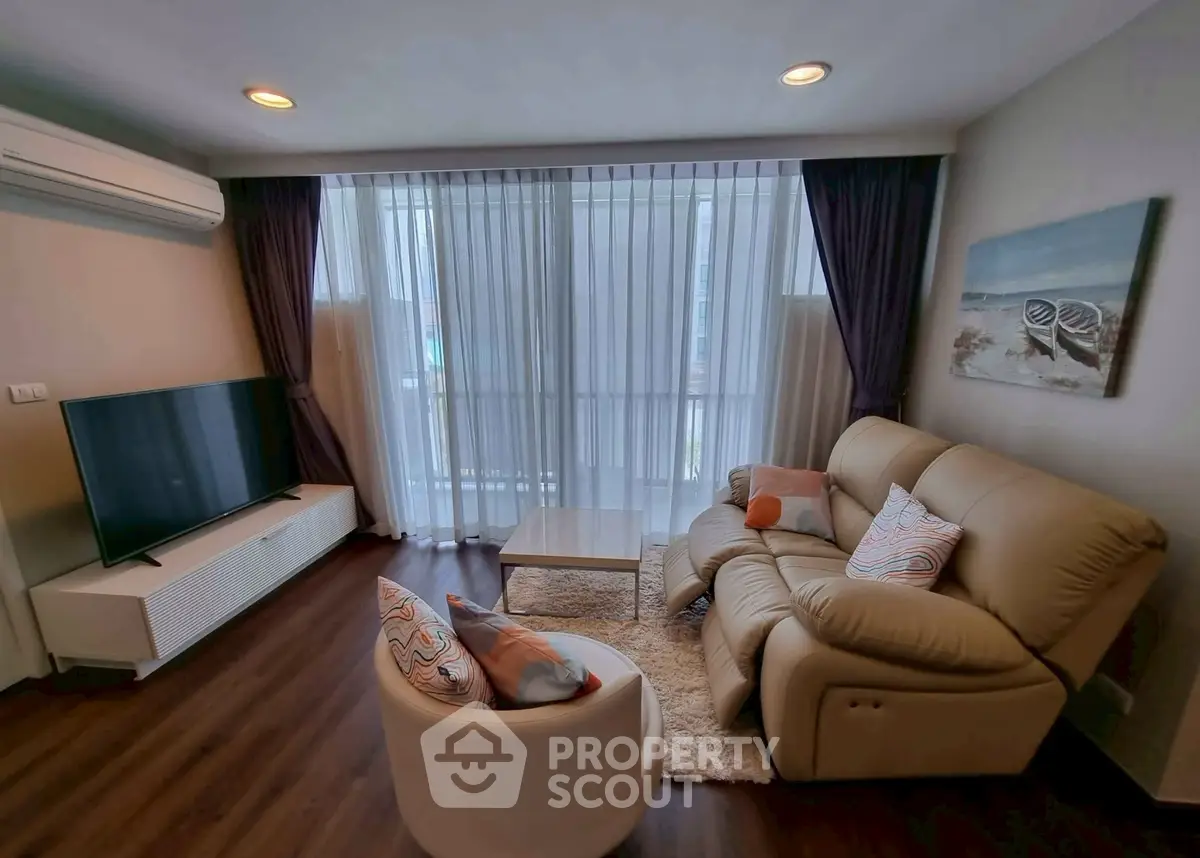 Cozy living room with modern decor, featuring a plush sofa, large TV, and elegant curtains.