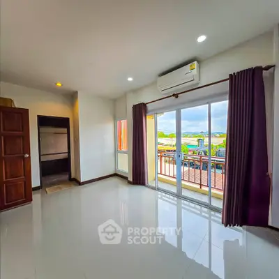 Spacious living room with balcony and scenic view, featuring modern air conditioning and elegant curtains.