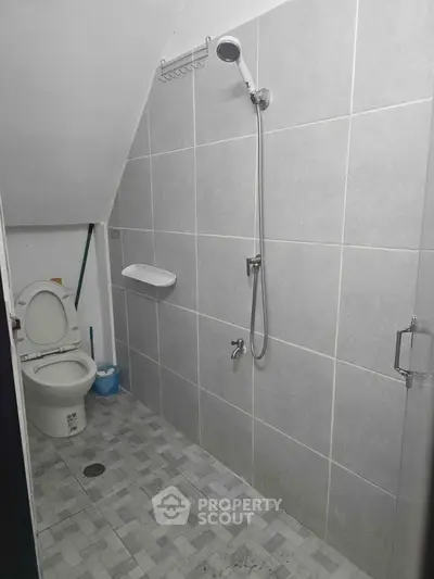 Compact bathroom with shower and toilet in modern gray tile design