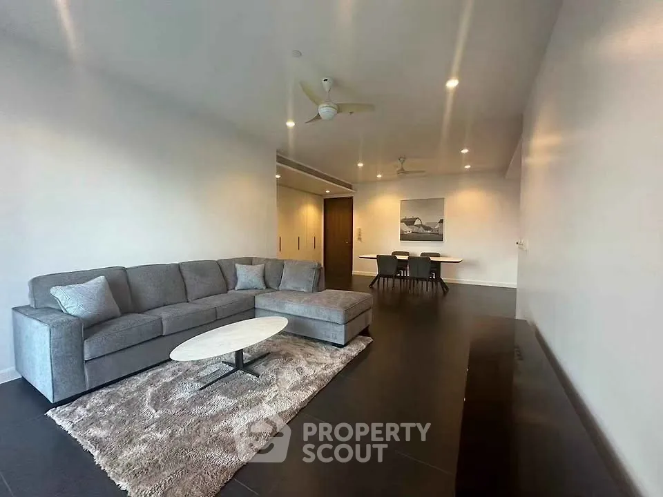 Spacious modern living room with elegant gray sofa and stylish dining area.